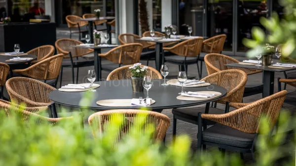 Terrasse eines Restaurants mit runden Tischen und Korbstühlen